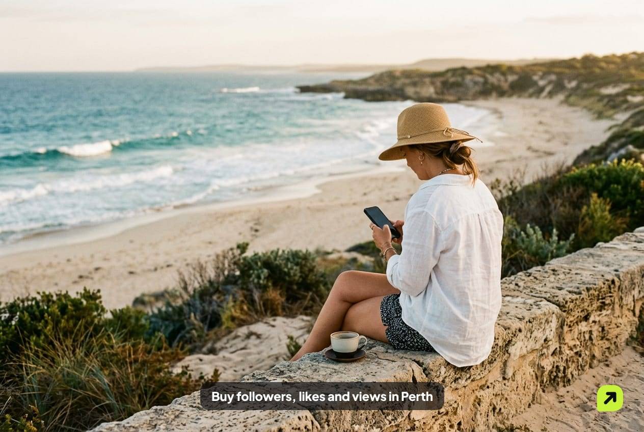 Woman in a sun hat on a limestone wall above a quiet Perth beach in late-afternoon light, looking at her phone