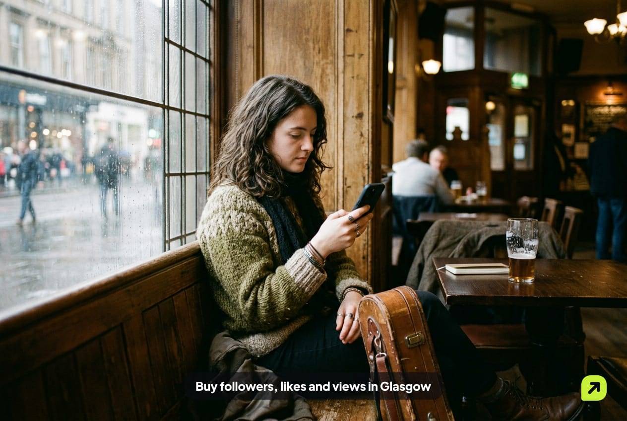 Fiddle player in a knitted sweater in a wood-paneled Glasgow pub window on a wet afternoon, looking at her phone