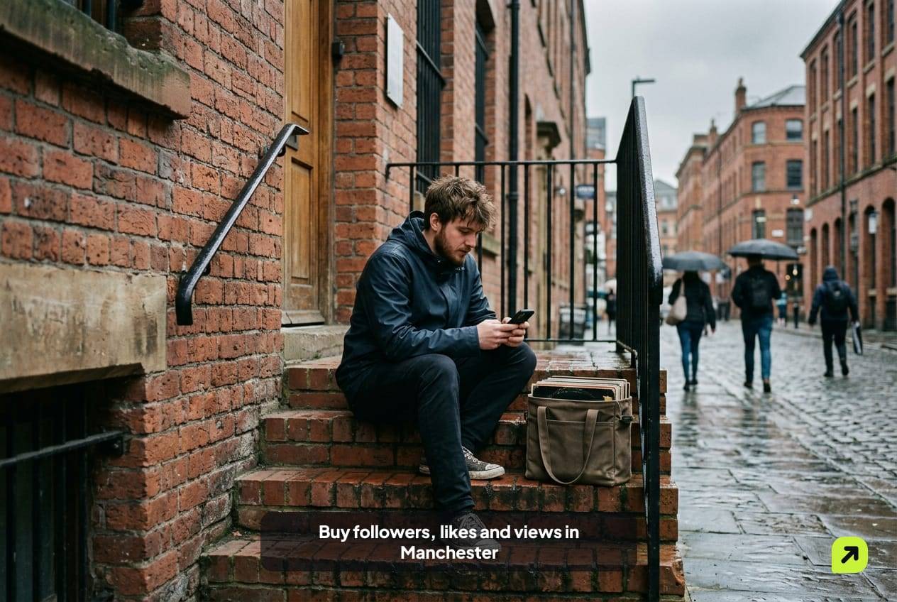 Young man in a rain jacket on warehouse steps in Manchester's Northern Quarter, record bag beside him, scrolling his phone
